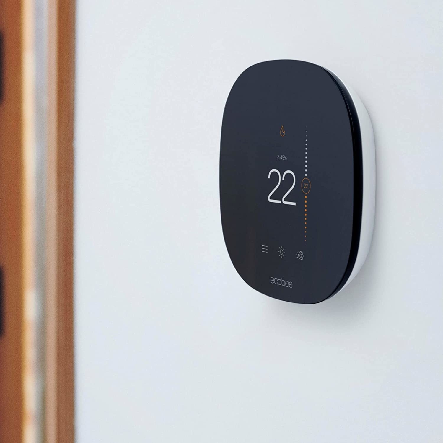 A sleek touchscreen smart thermostat on a wall in a home