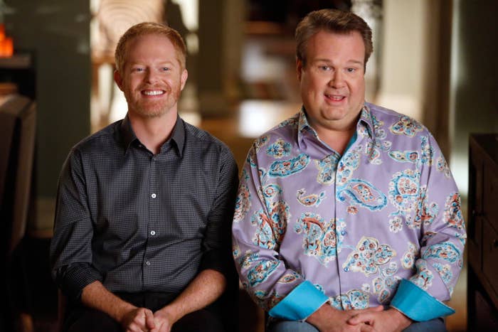 Mitch and Cam sitting next to each other as they do a confessional during a scene in Modern Family