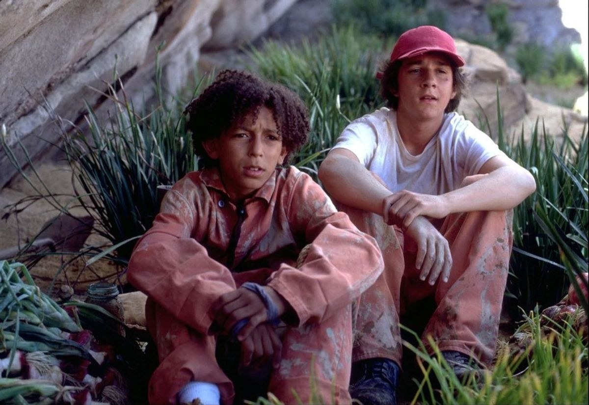 Khleo Thomas and Shia LaBeouf as Hector and Stanley looking muddy and tired as they sit surrounded by fresh onions