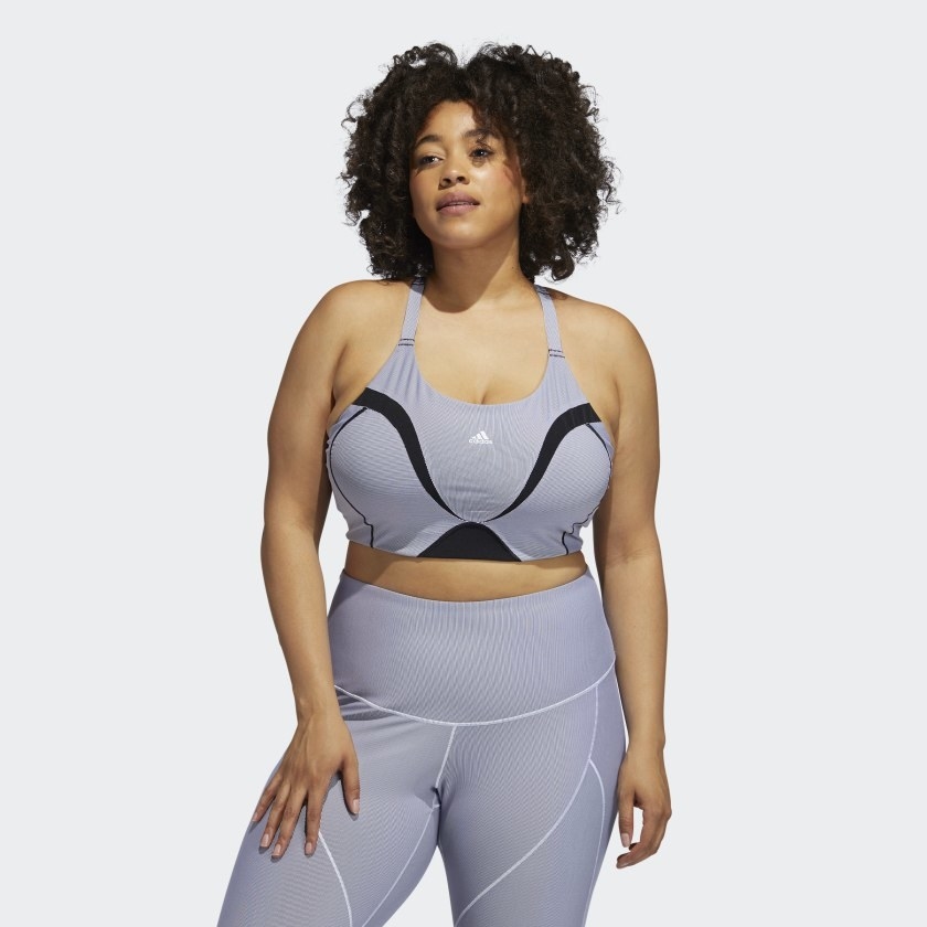 An image of a model wearing a plus size sports bra in grey/white