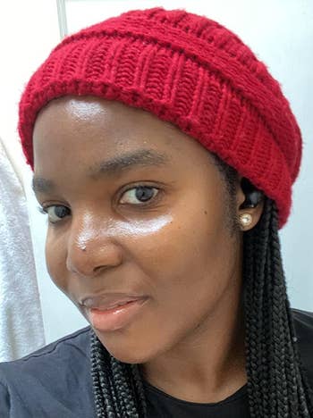 reviewer with braids wearing the red knitted beanie