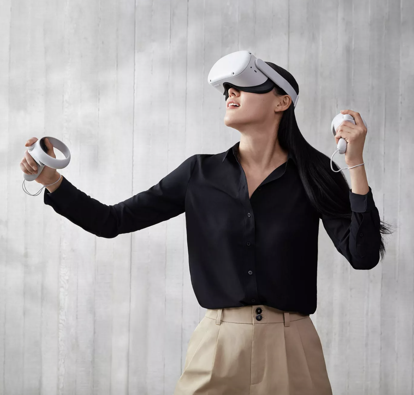Model is wearing the Oculus VR headset and holding the remote controls in their hand