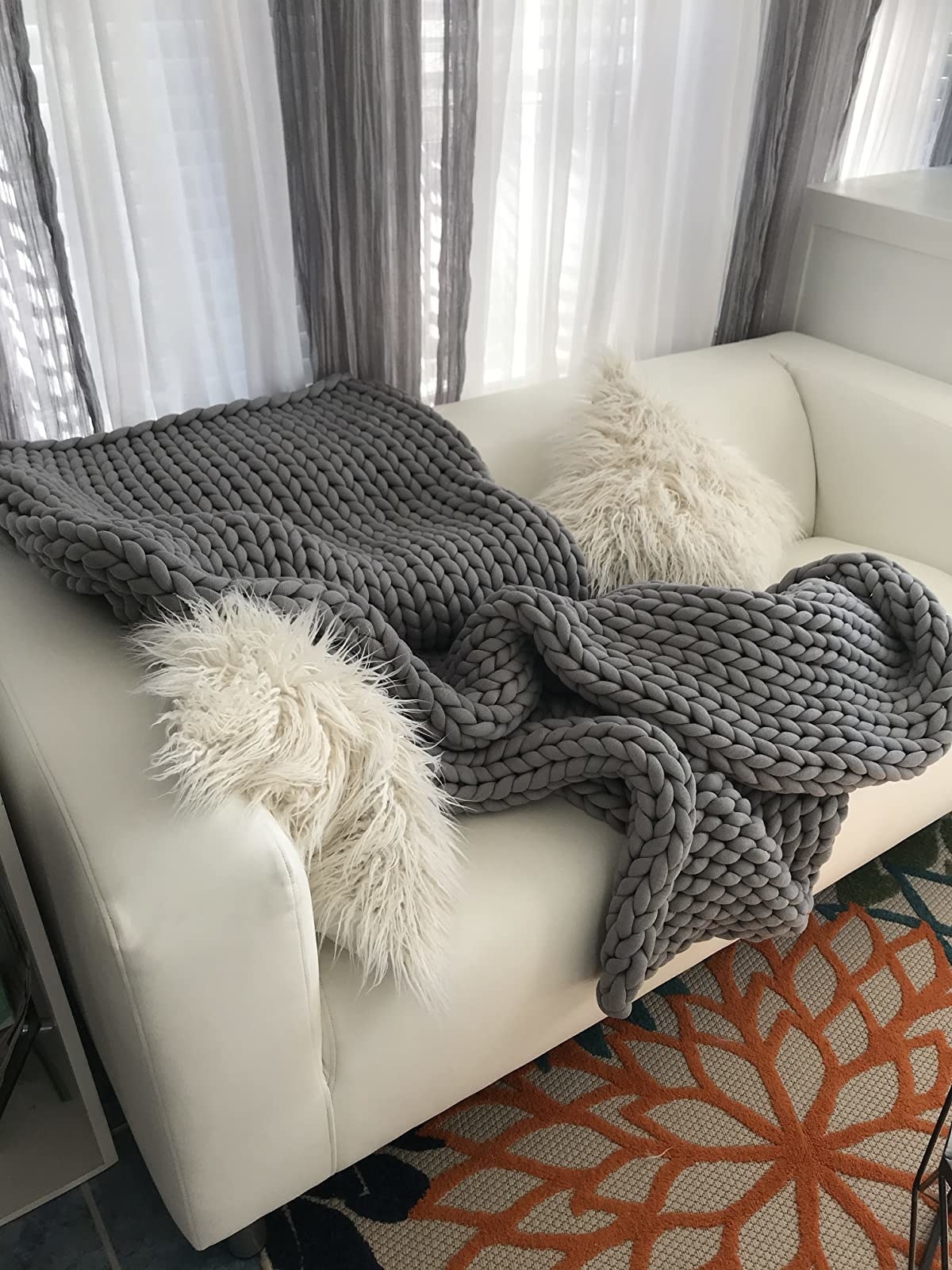 a reviewer shows  the gray blanket on a white couch