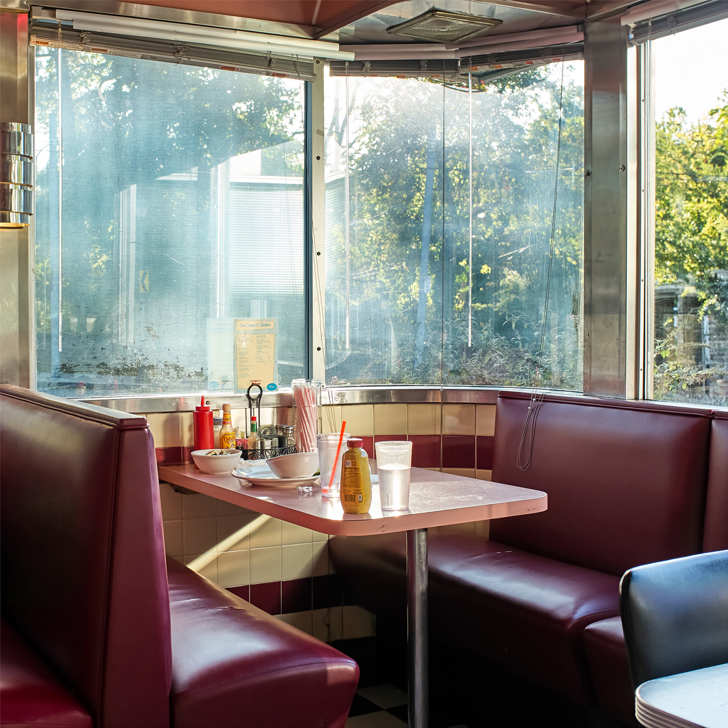 A diner car with a bottle of mustard and two glasses of water on the table 