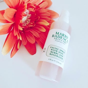 Reviewer photo of the face spray bottle next to an orange flower