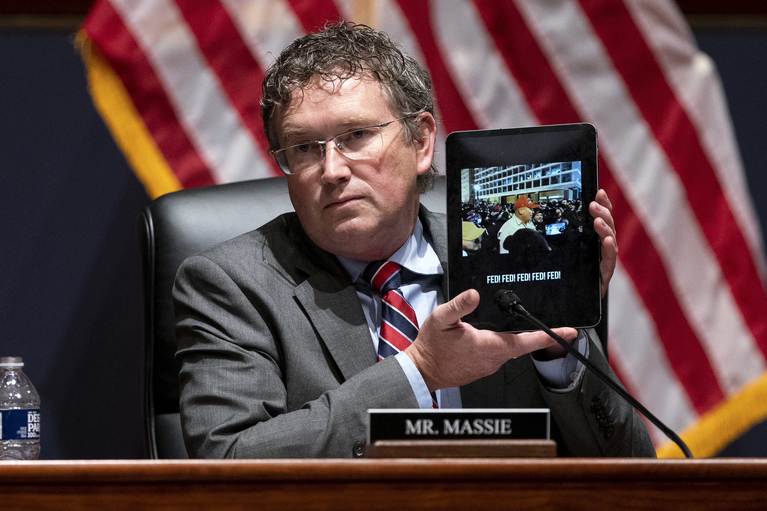 Massie at a hearing about the insurrection holding up a video from that day on his tablet