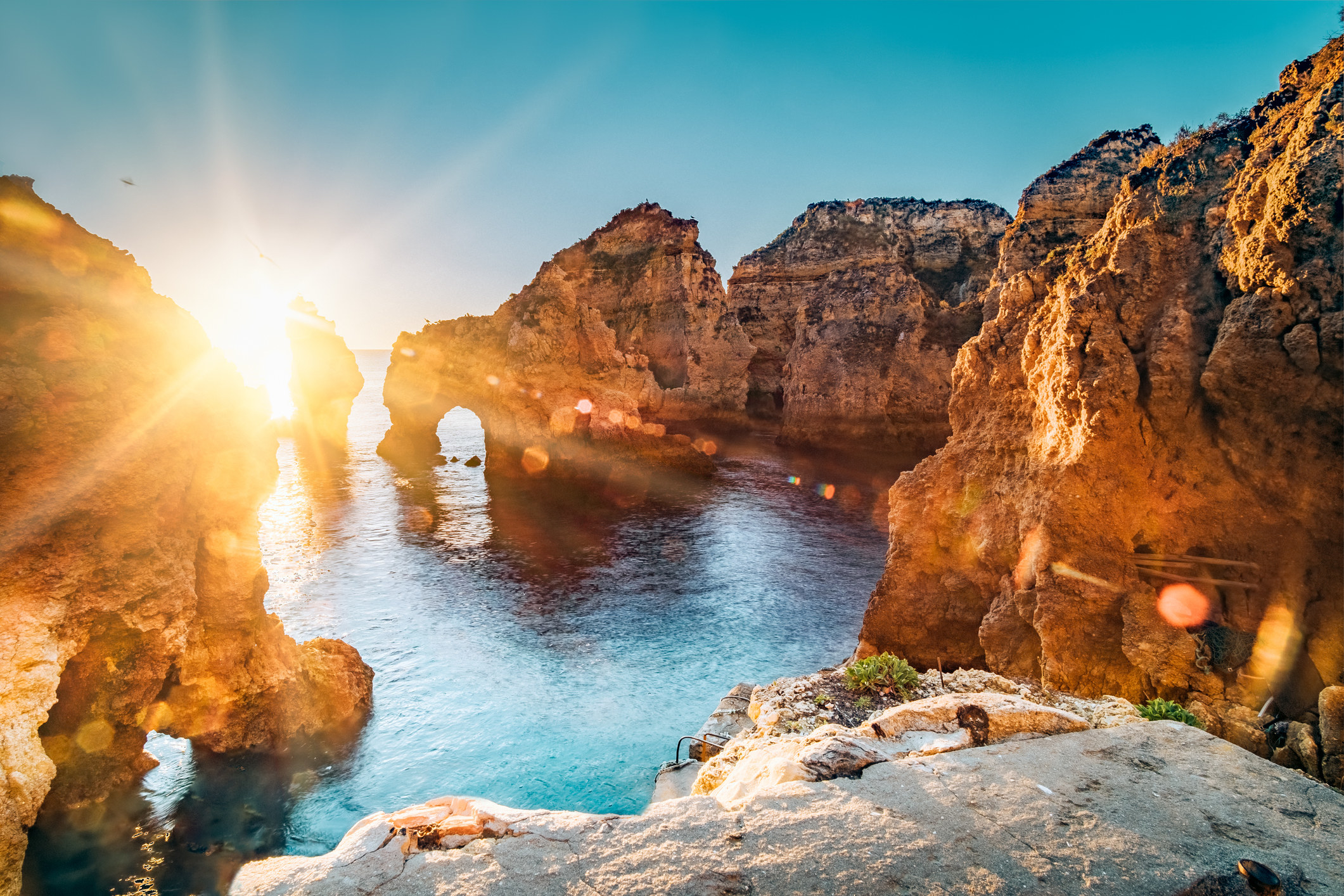 Golden sunrise over cliffs and water.