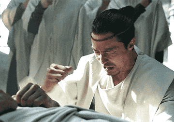 Lan Mandragoran banging his hand against his chest while leaning on the floor