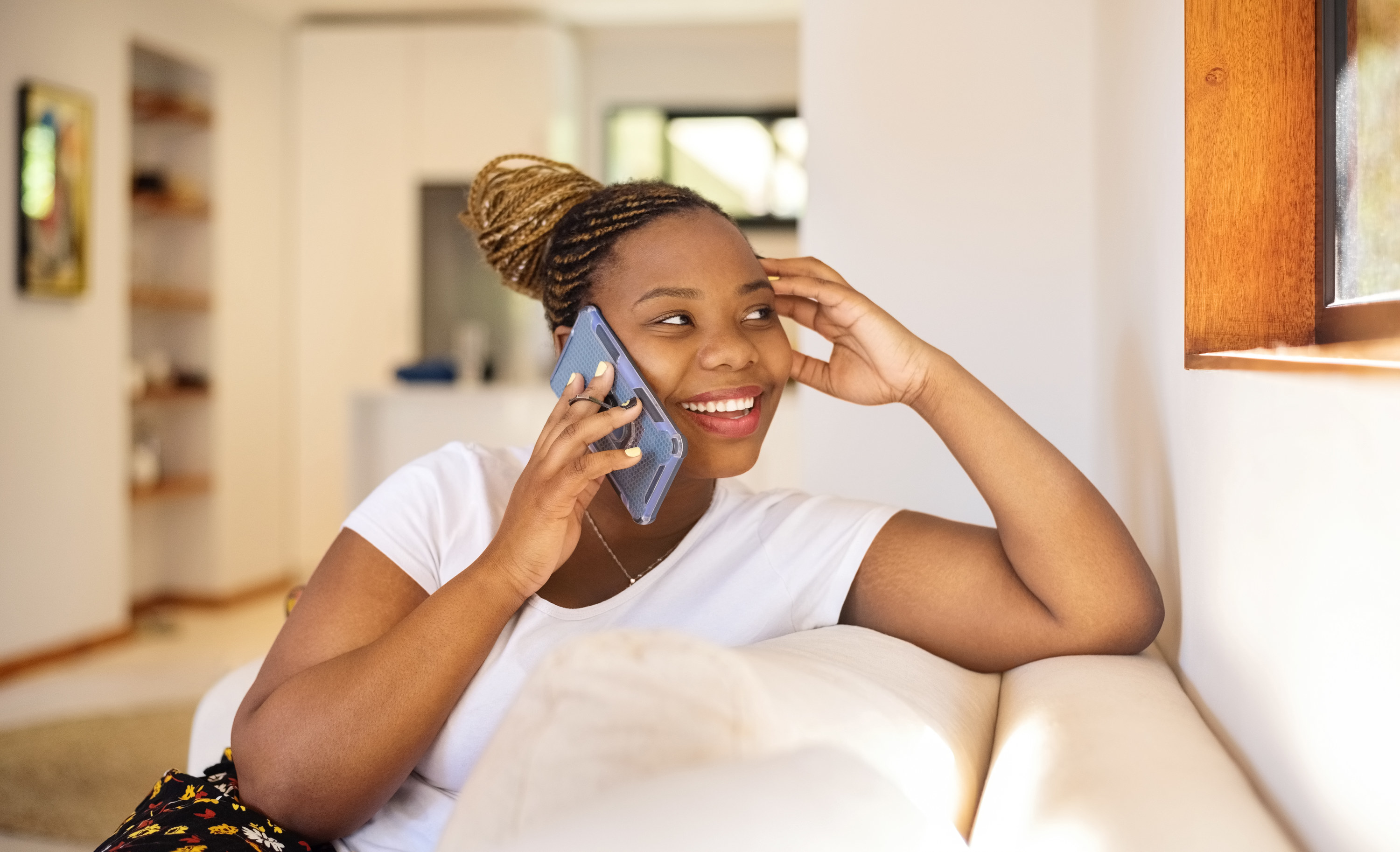 A woman relaxes on the couch while smiling and talking on the phone