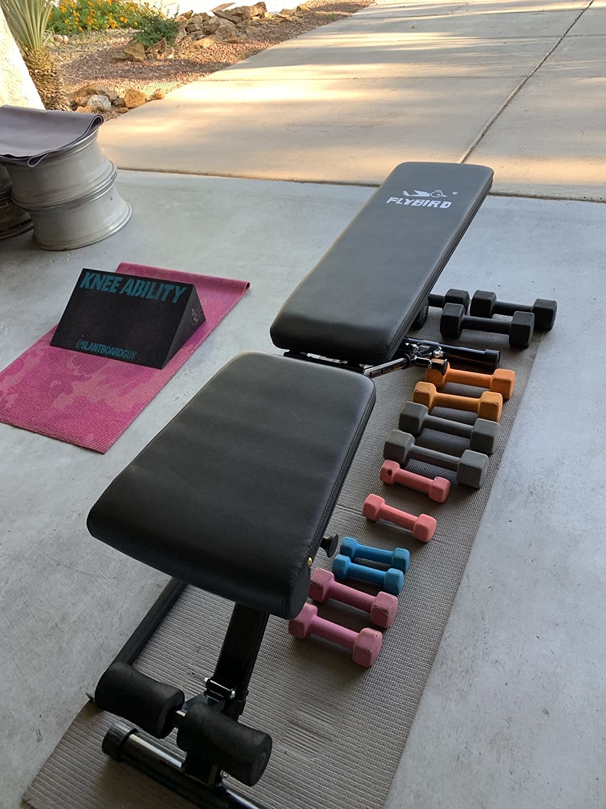 Reviewer photo of the bench with dumbbells underneath it