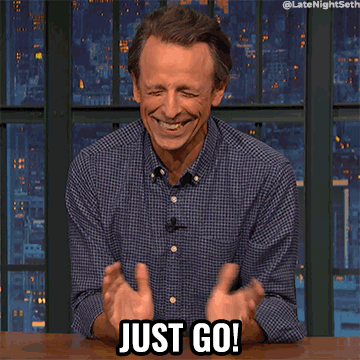 Seth Meyers sits at a desk and laughs as he waves his hand and says