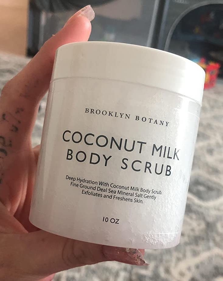 reviewer holding a tub of the body scrub