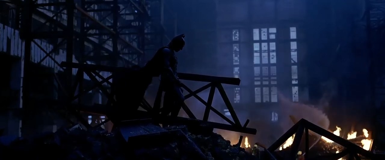 Batman standing atop the rubble of a burning and ruined warehouse in &quot;The Dark Knight&quot;