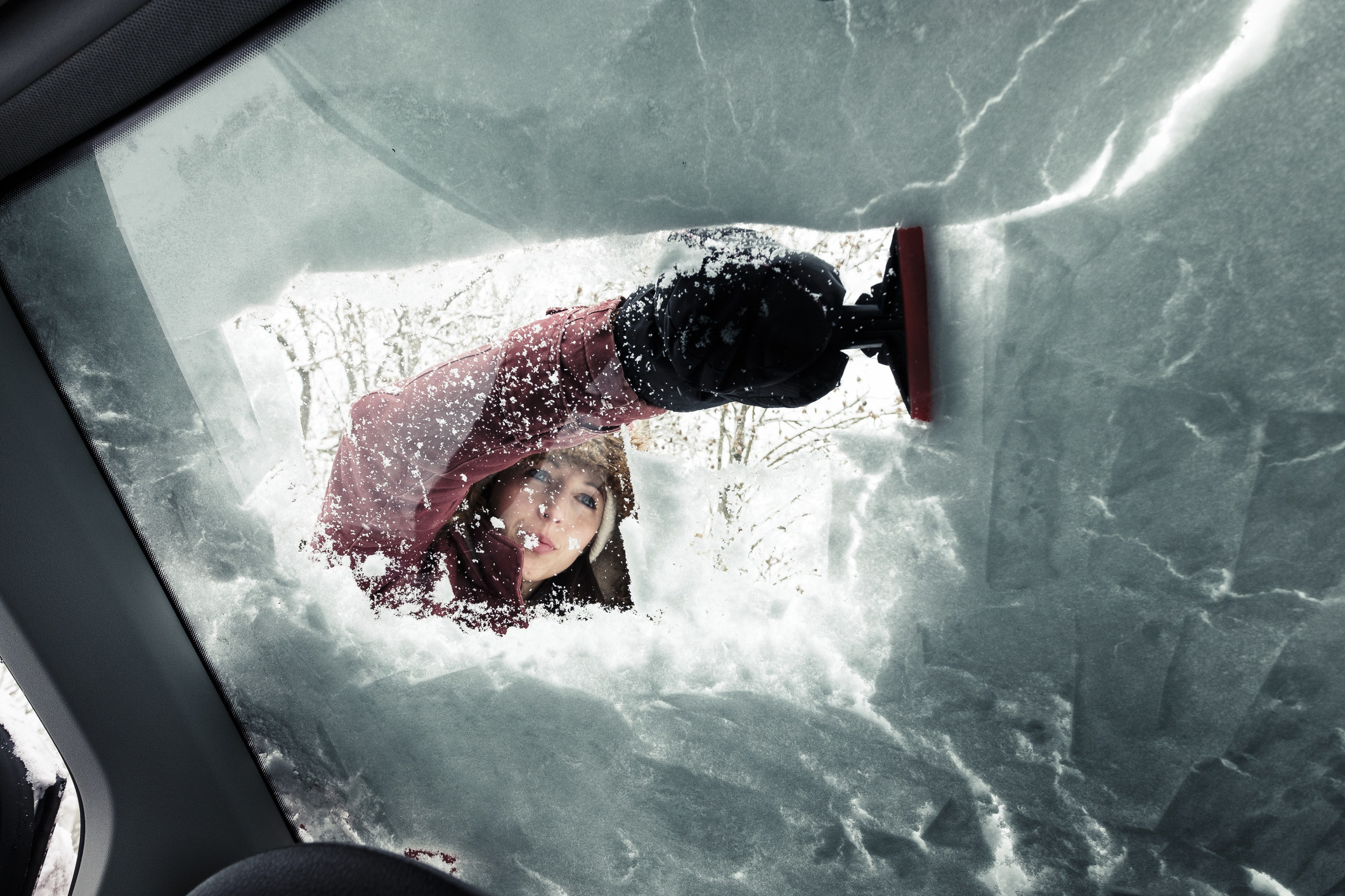 woman cleaning snow from car&#x27;s windshield
