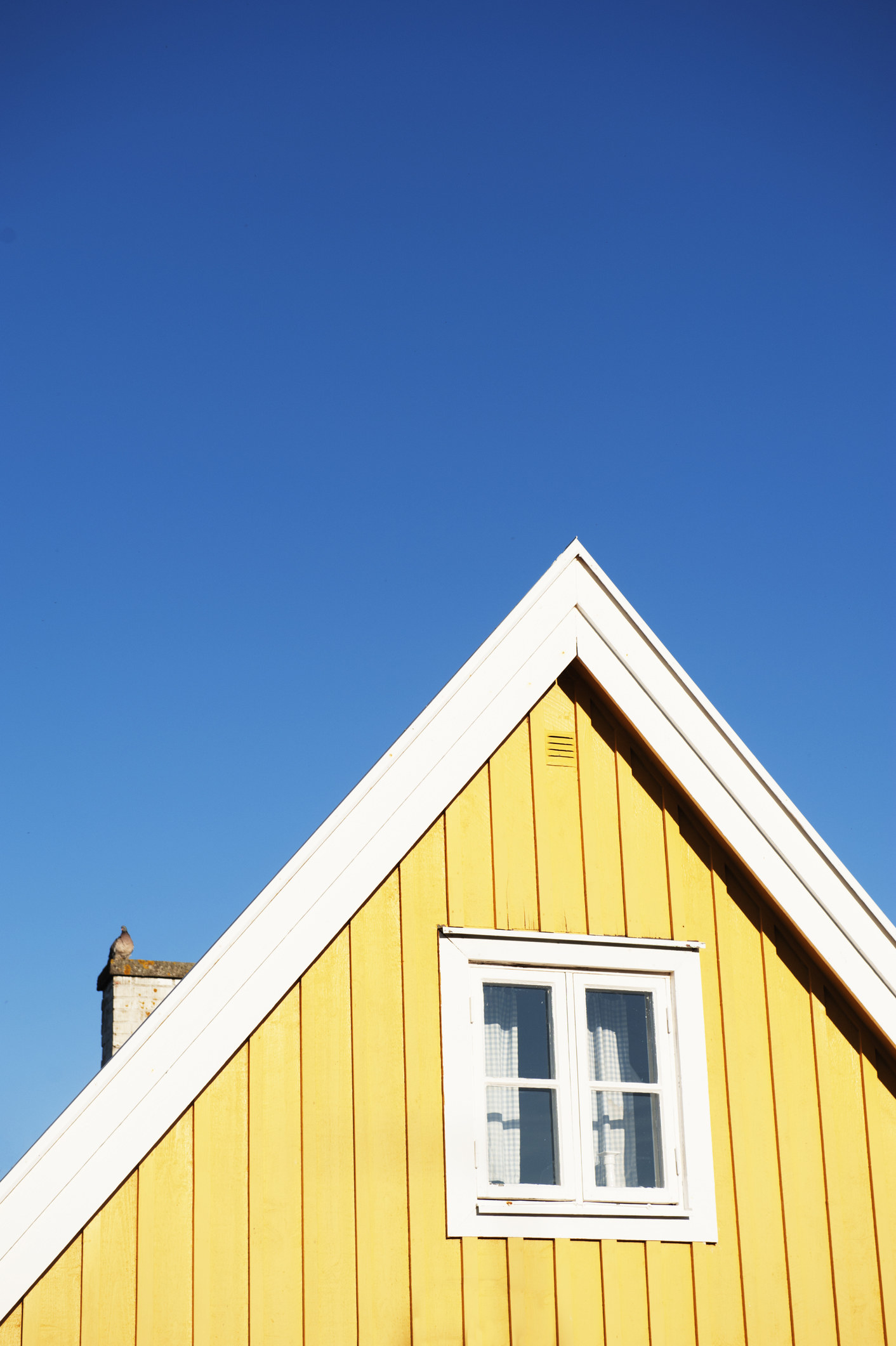 A yellow house with blue skies behind it