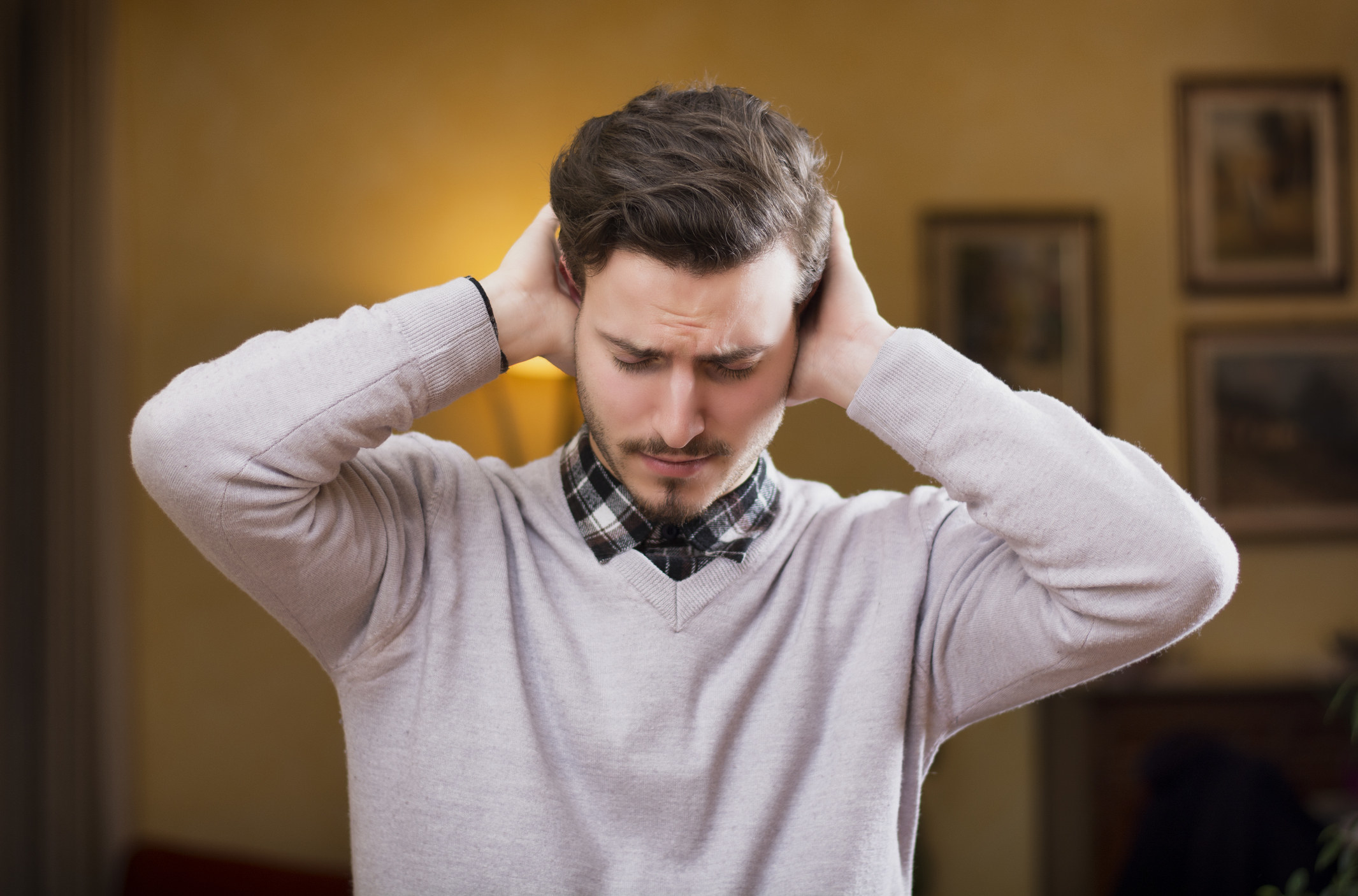 Man covering his ears, stressed or unhappy because of too much noise.