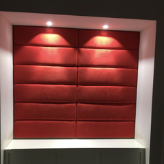 headboards in red placed on a wall under lights