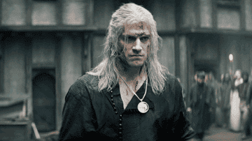 Henry Cavill as Geralt walks with blood stains on his face in