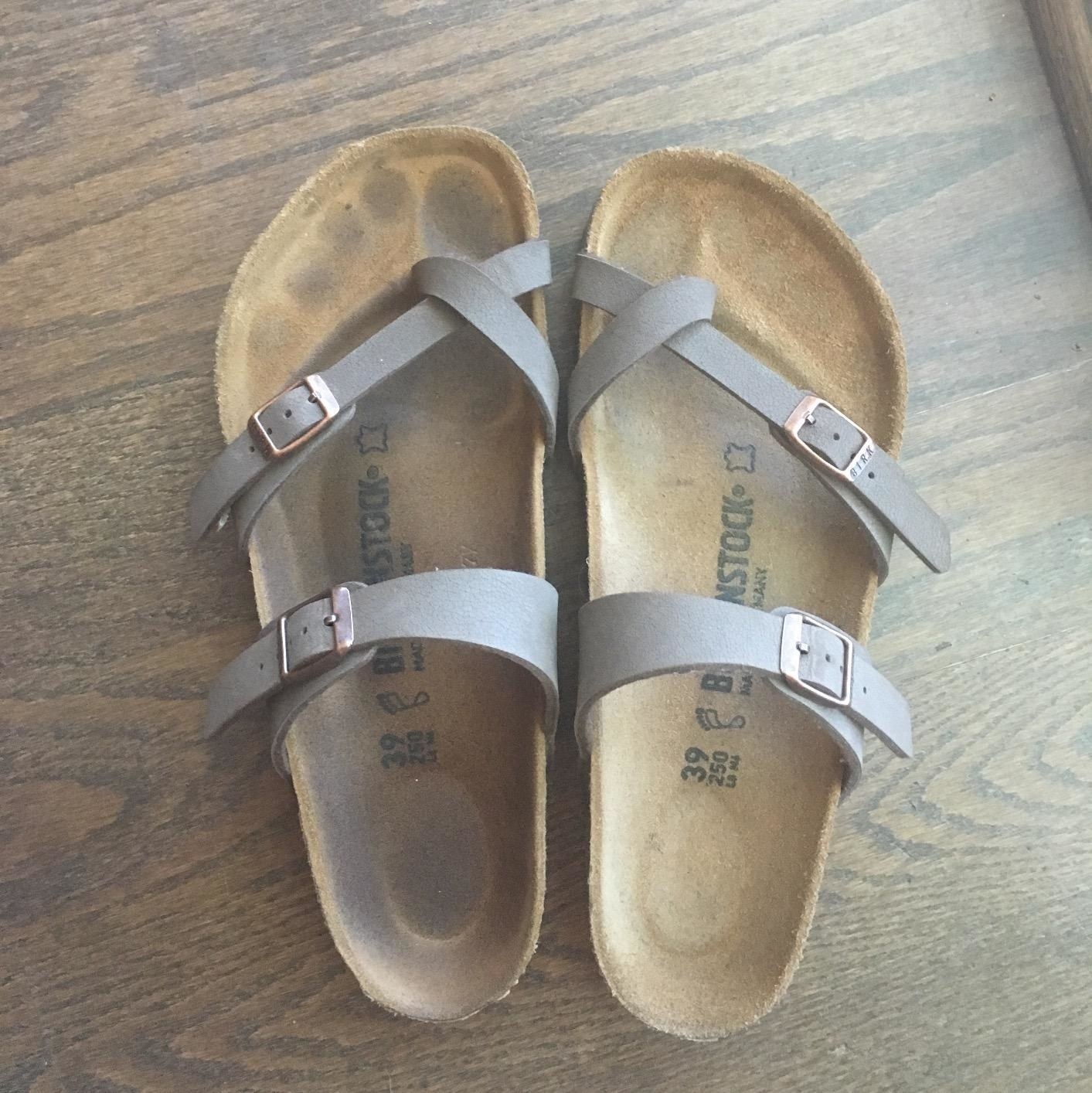 reviewer shows a pair of sandals with suede soles, one has a dirty foot outline and the other is clean after using the brush
