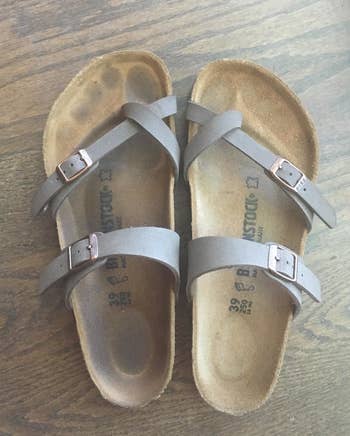 reviewer shows a pair of sandals with suede soles, one has a dirty foot outline and the other is clean after using the brush