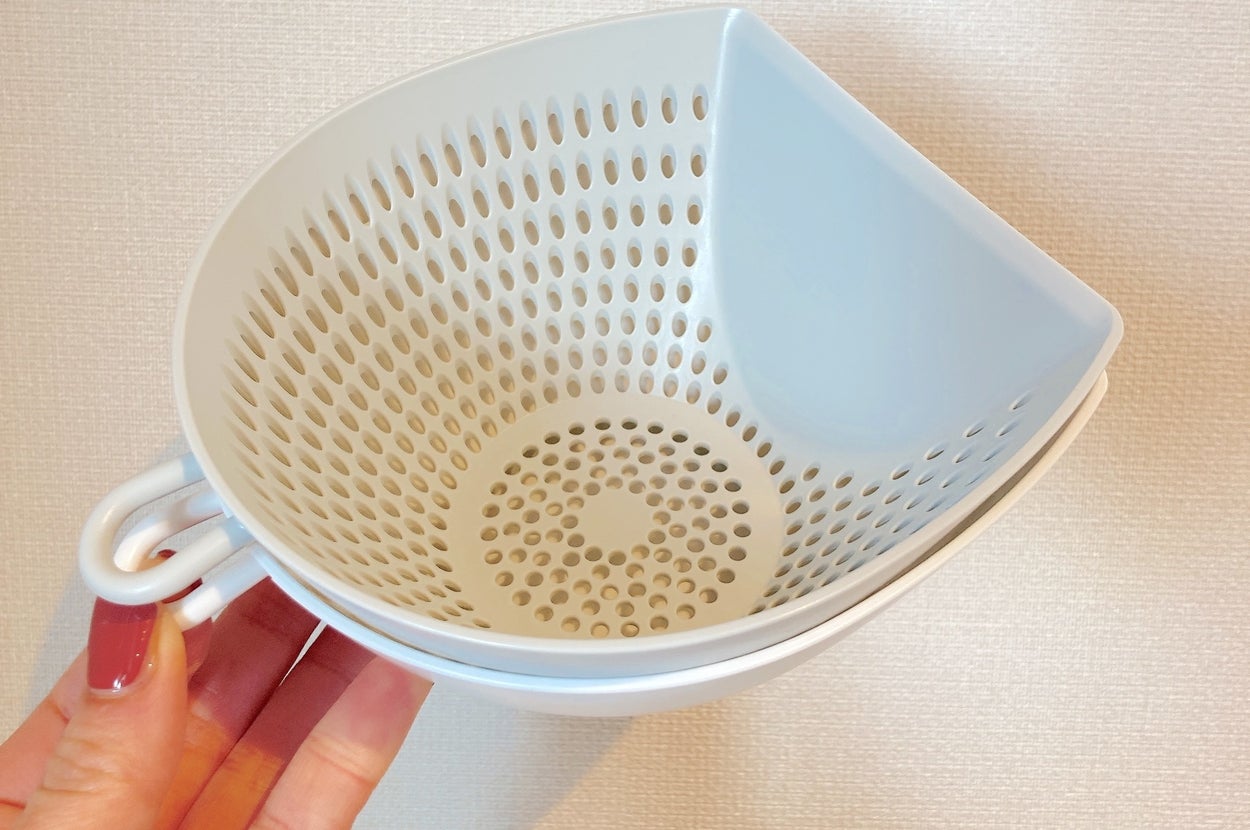 穴のあるプラスチック製の白い水切りボウルを手で持っている様子。