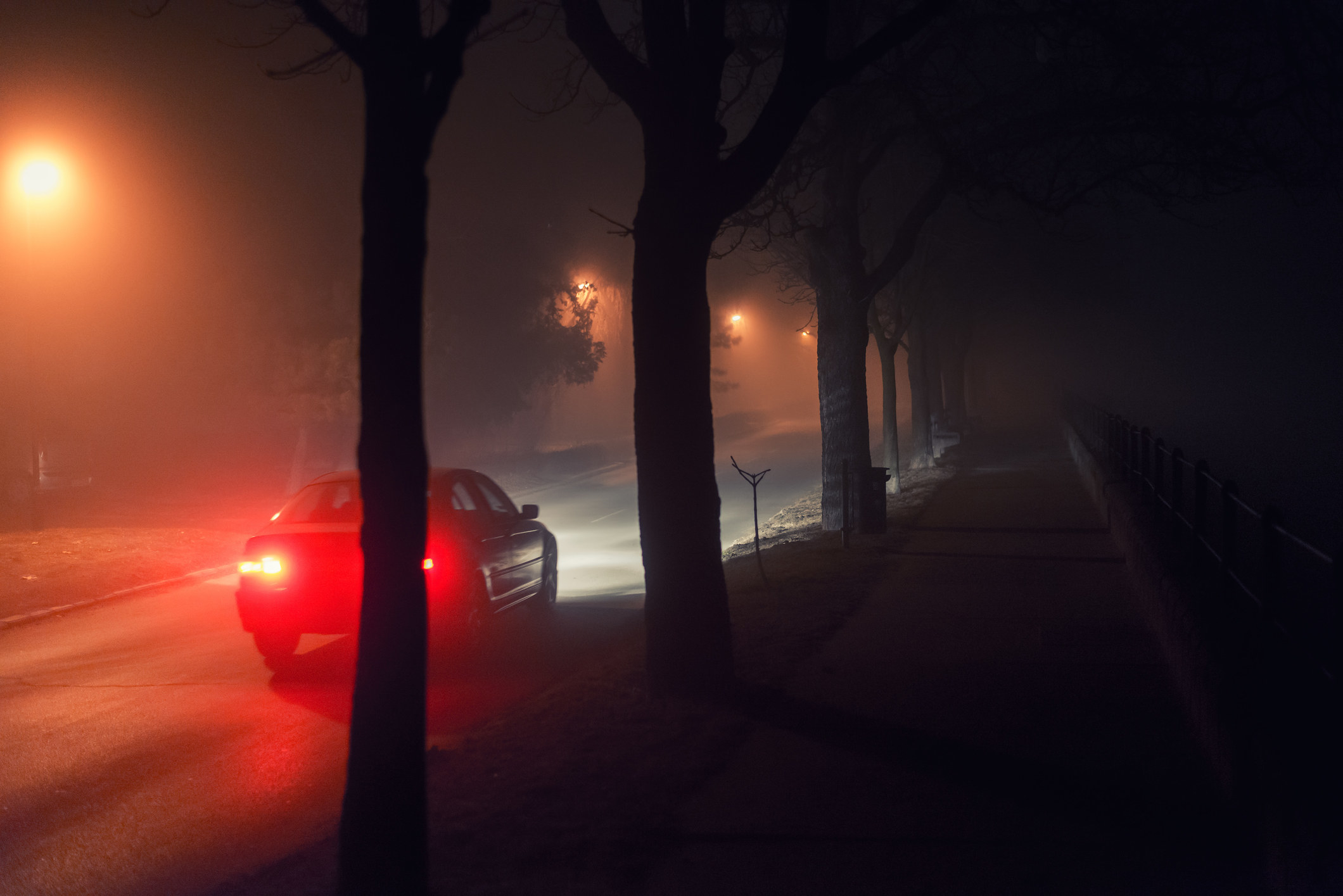 Pedestrian walkway and car moving through the city on misty winter night