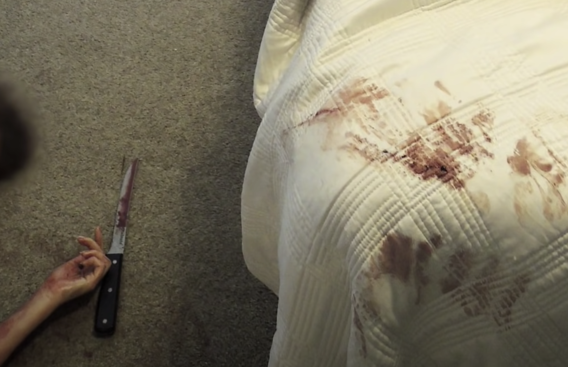 Crime scene photo of a dead woman&#x27;s arm next to a bloody knife and blood-stained bed