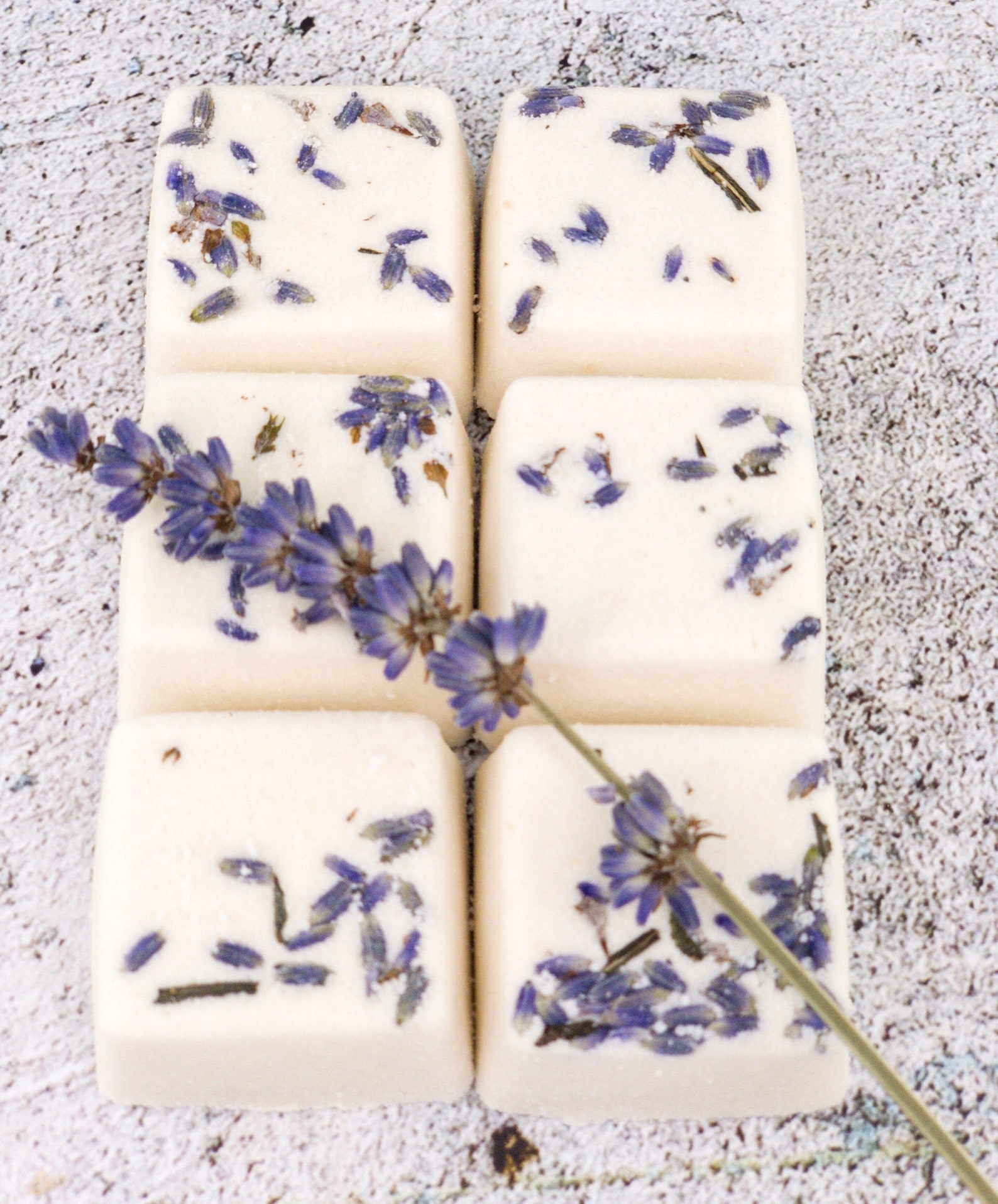 The pack of lavender shower steamers next to some fresh lavender
