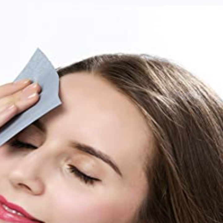 A person using the blotting paper on their forehead
