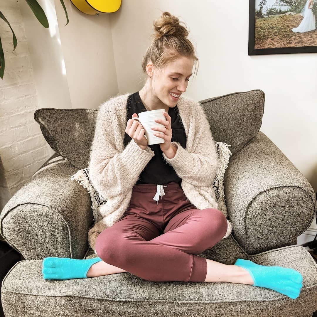 someone sipping tea on an armchair while wearing the moisturizing socks