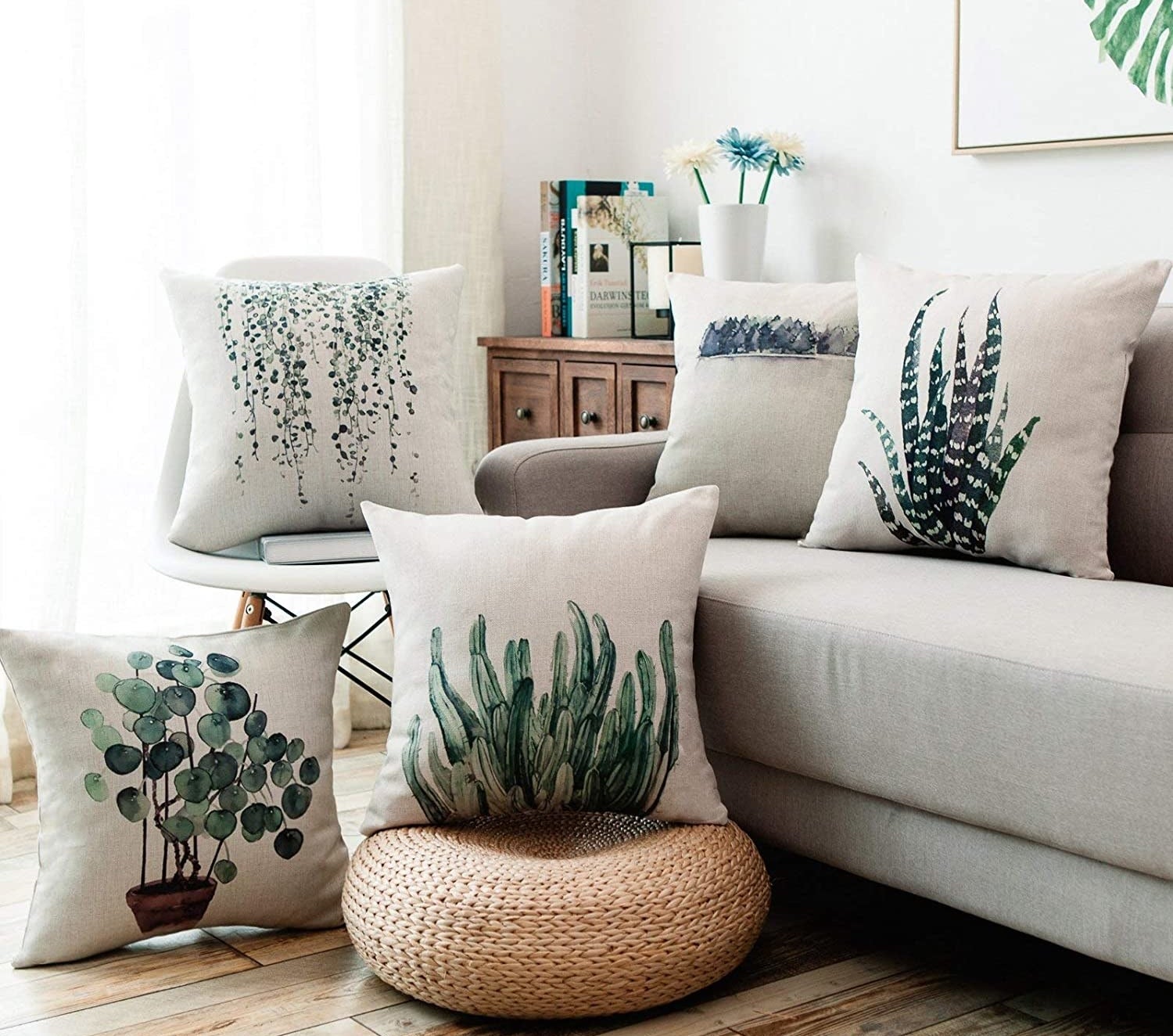 a couch with a set of four throw pillows on it each with a print of a different plant