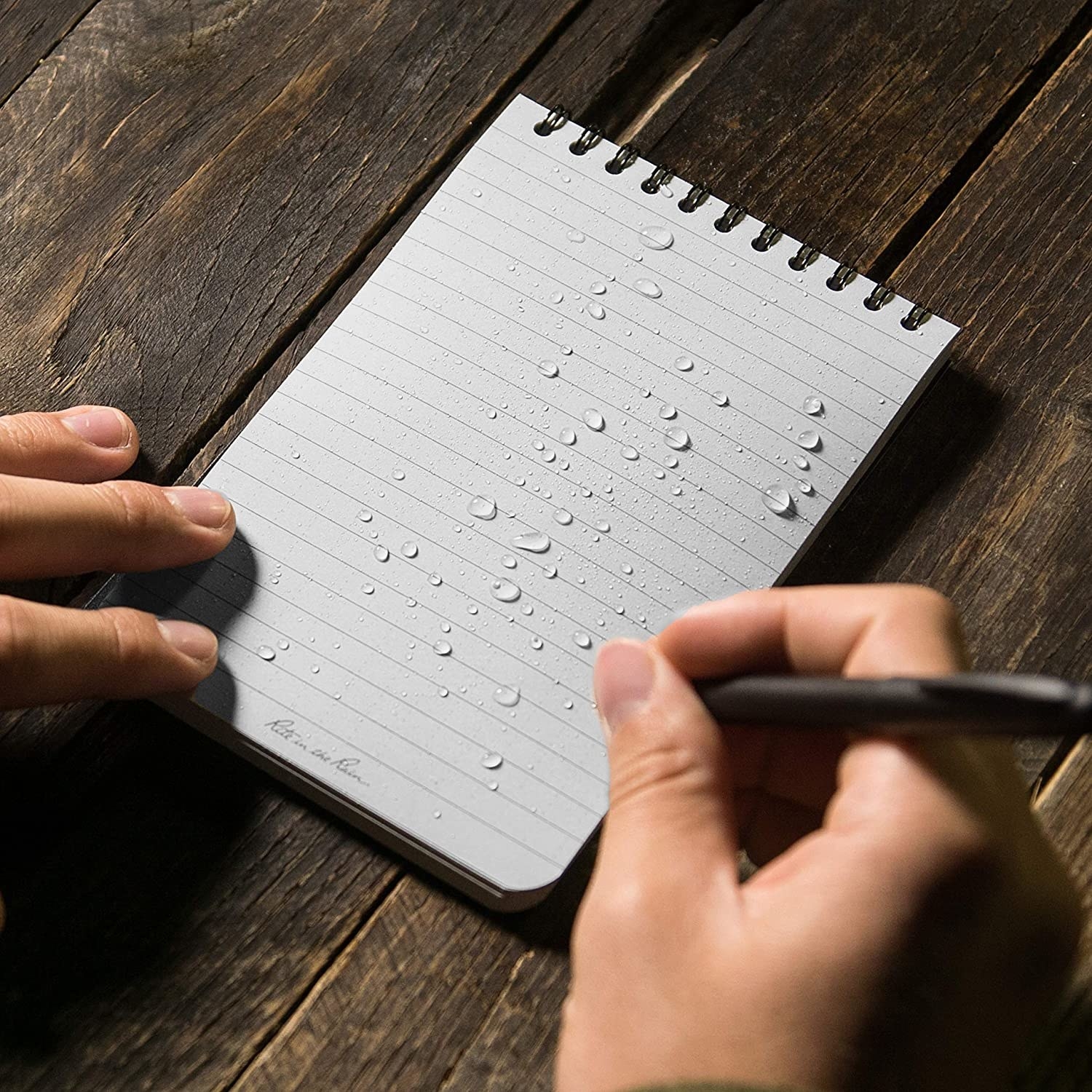 a person using the waterproof notepad with water droplets on it