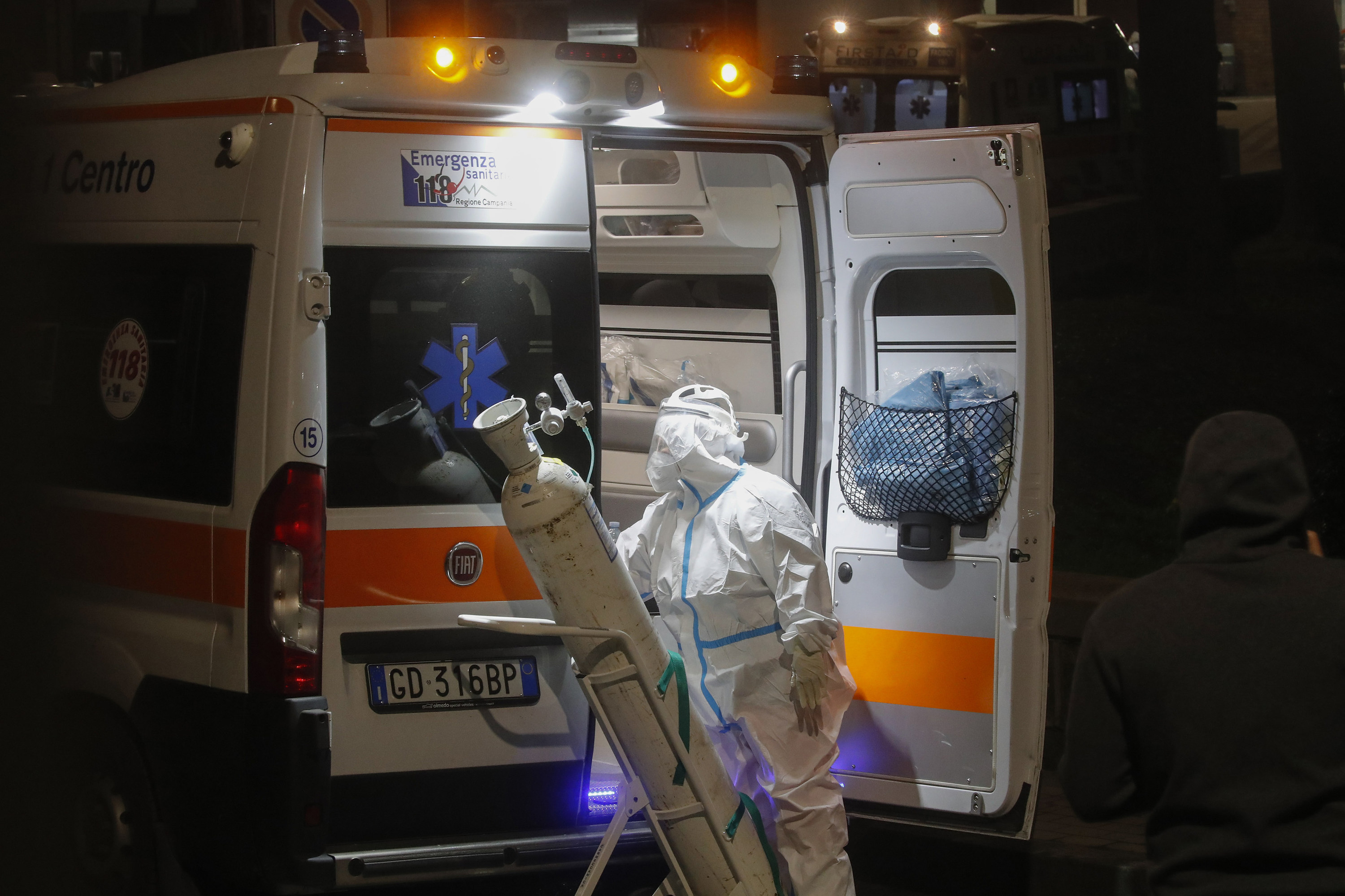A nurse with an oxygen cylinder next to an ambulance