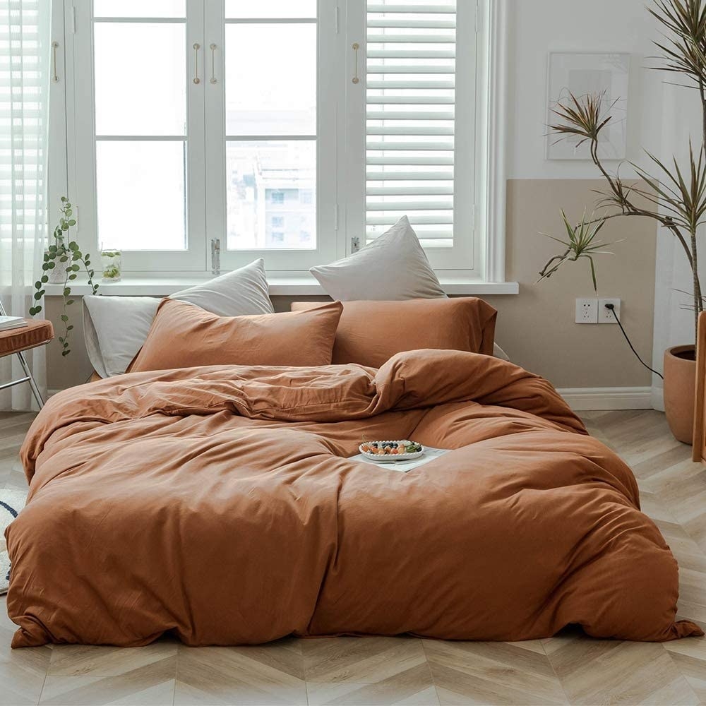 mattress on the floor covered in a soft pumpkin colored duvet