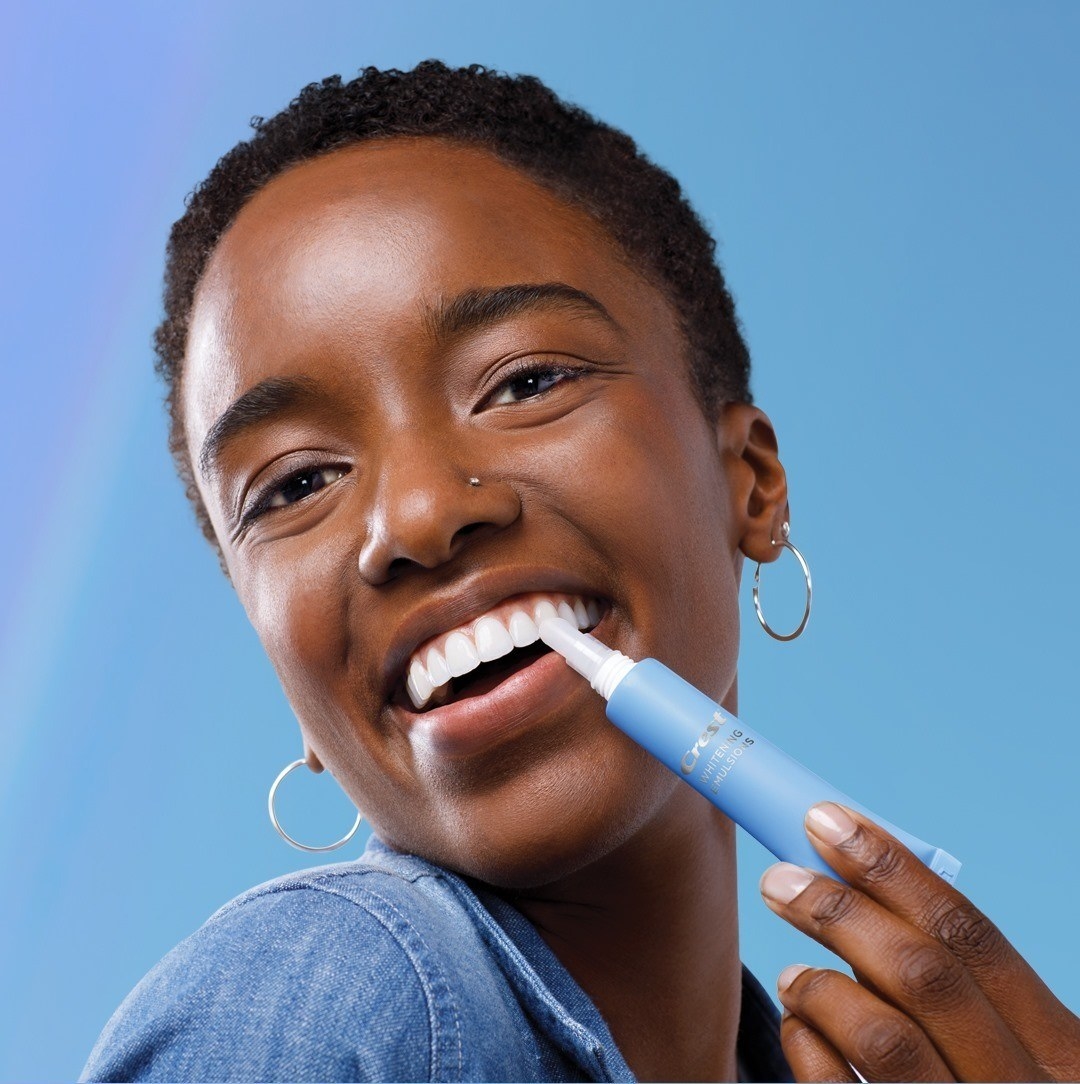 a smiling person using the whitening pen on their teeth