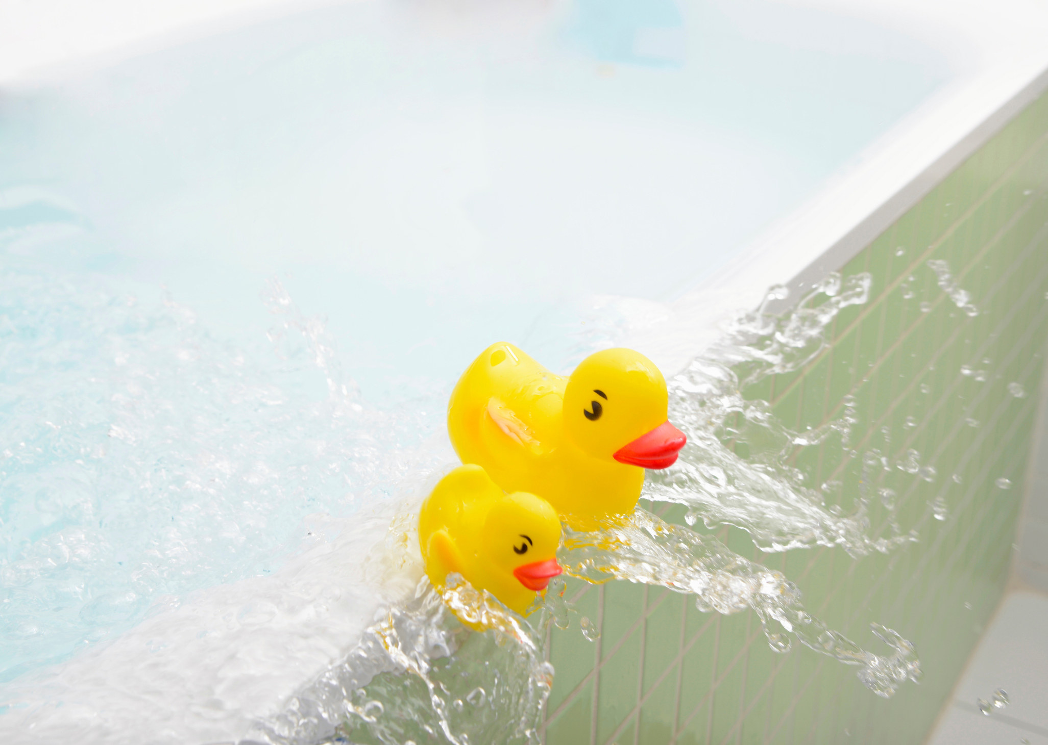 Rubber ducks falling out of bath overflowing with water