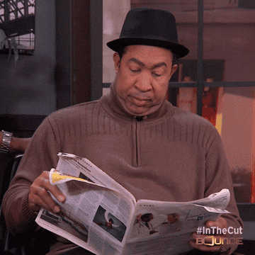 man putting a newspaper in front of his face