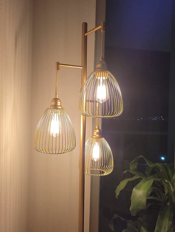 closeup of reviewer's lamp. it has three edison bulbs covered in wire shades and stands on its own.