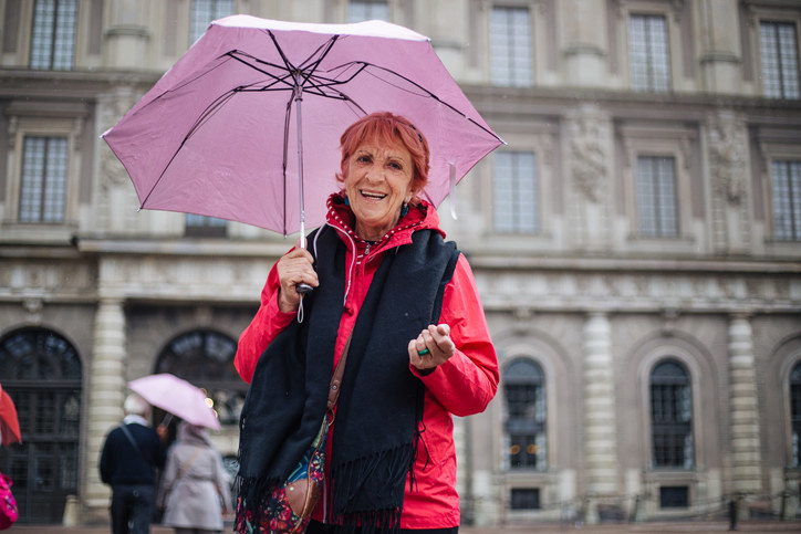 Senior adult woman walking around Stockholm with an umbrella during a rainy day