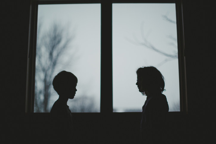 The silhouette of a boy and girl in front of a window