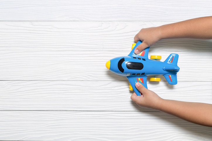 A pair of hands play with a blue toy plane