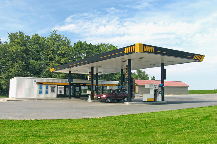 A gas station surrounded by green grass and trees