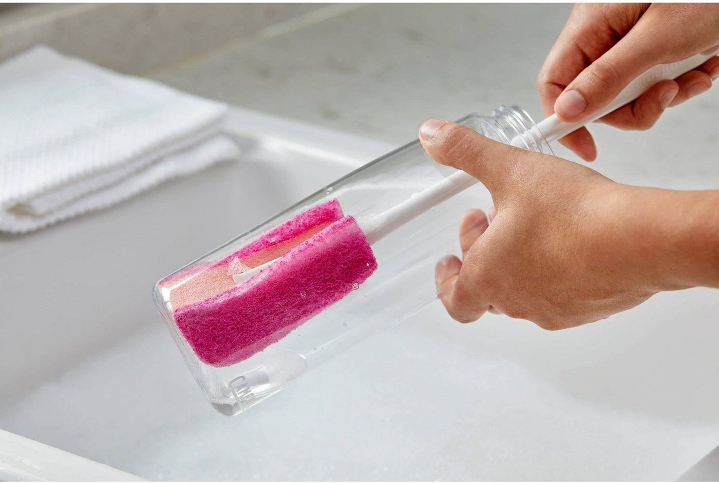 a model using the pink and white scrubber in a reusable water bottle