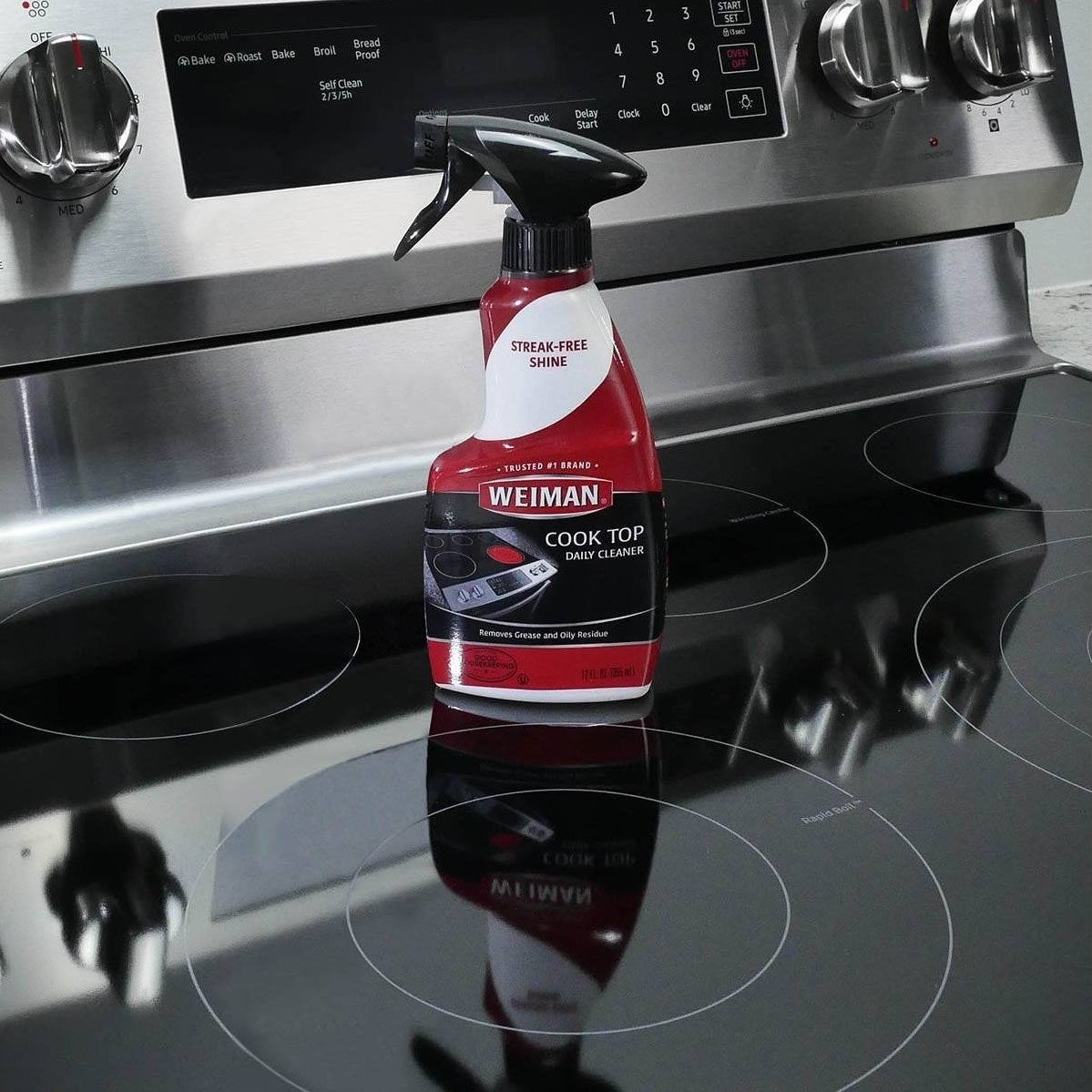 the red and black spray bottle of cleaner on a shiny glass cooktop