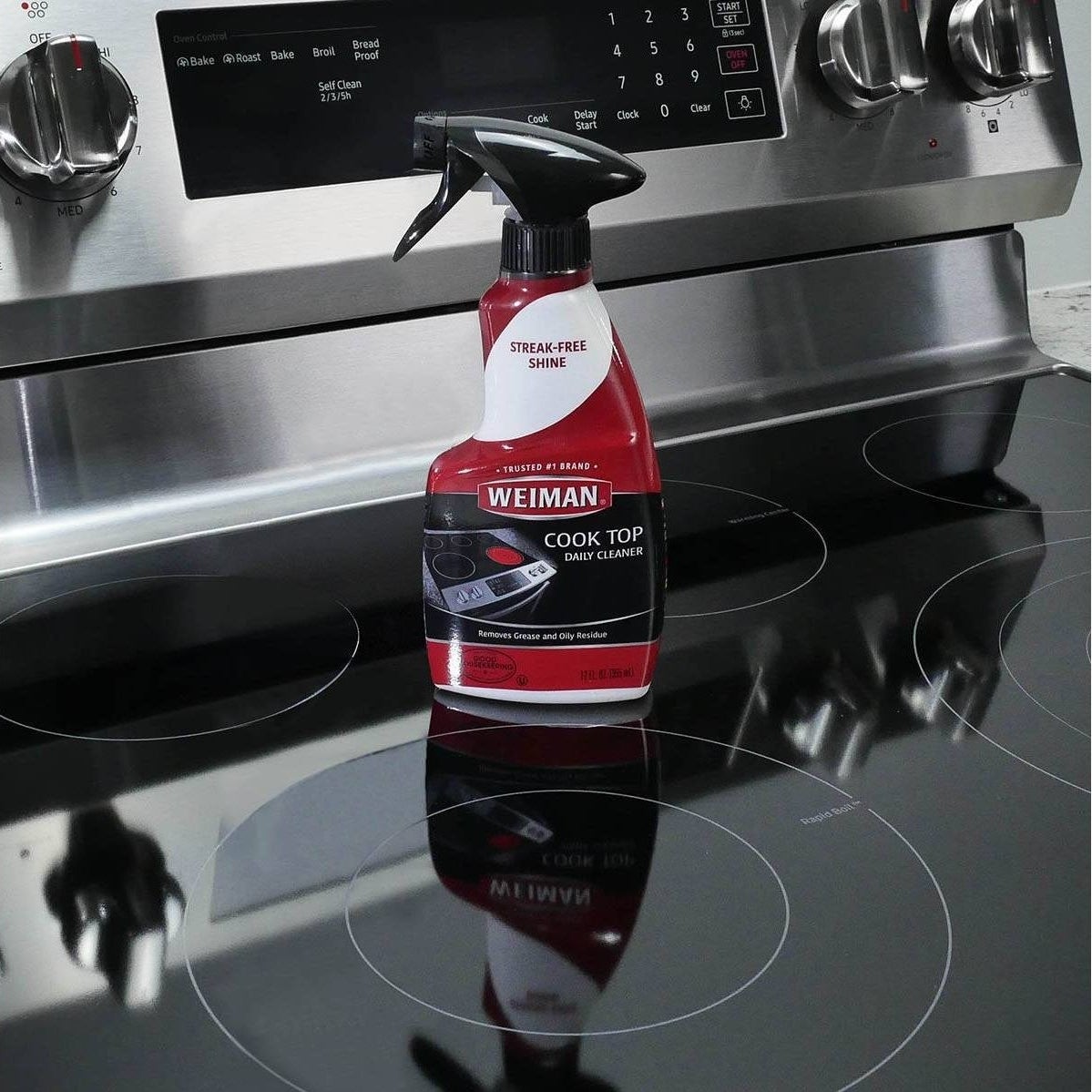 the red and black spray bottle of cleaner on a shiny glass cooktop