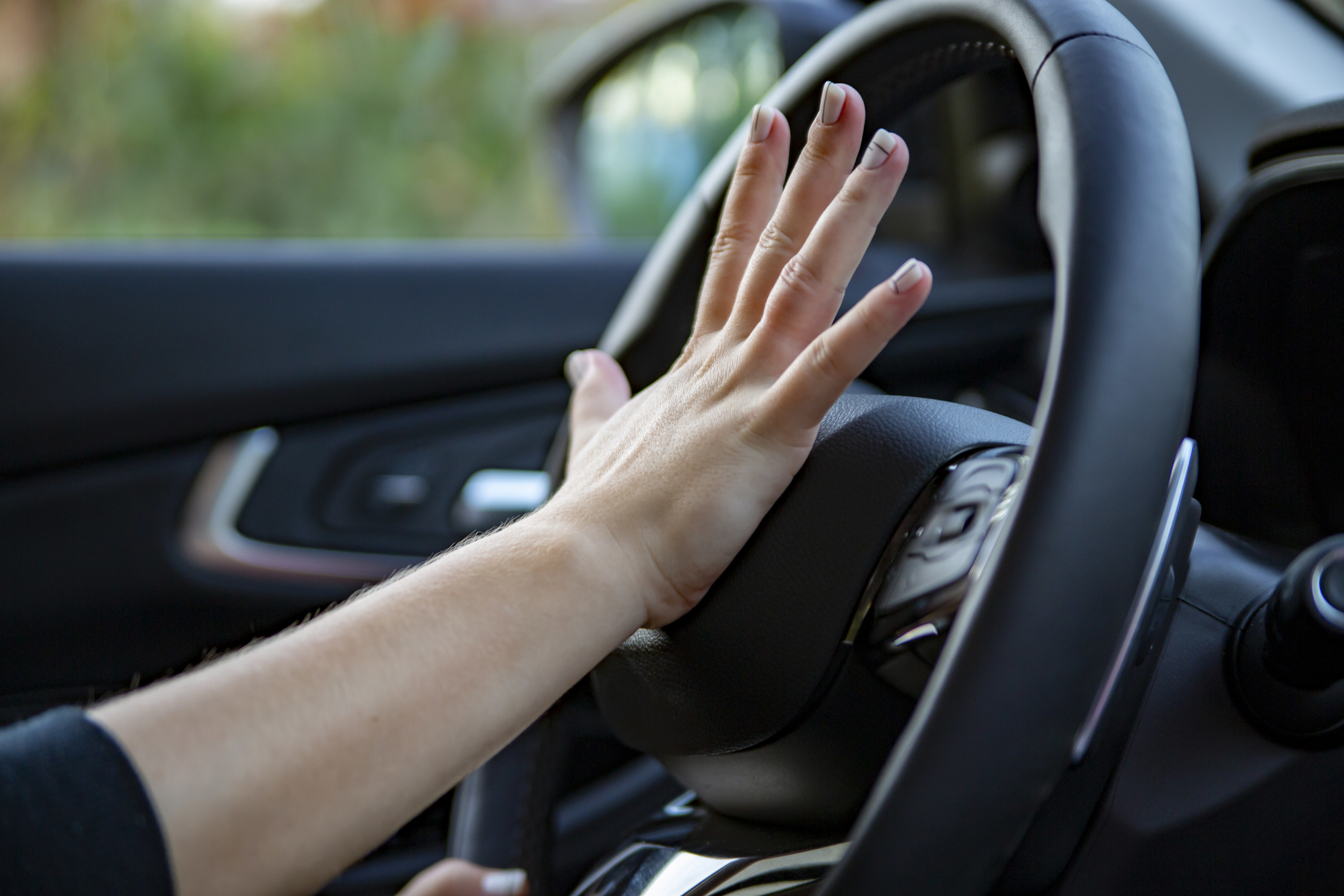 A close up image of a hand honking a car horn