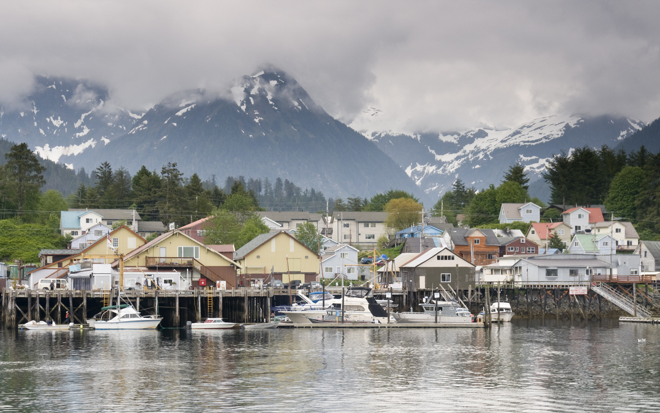 Colorful buildings and boats on a harbor with snowy mountains in the background