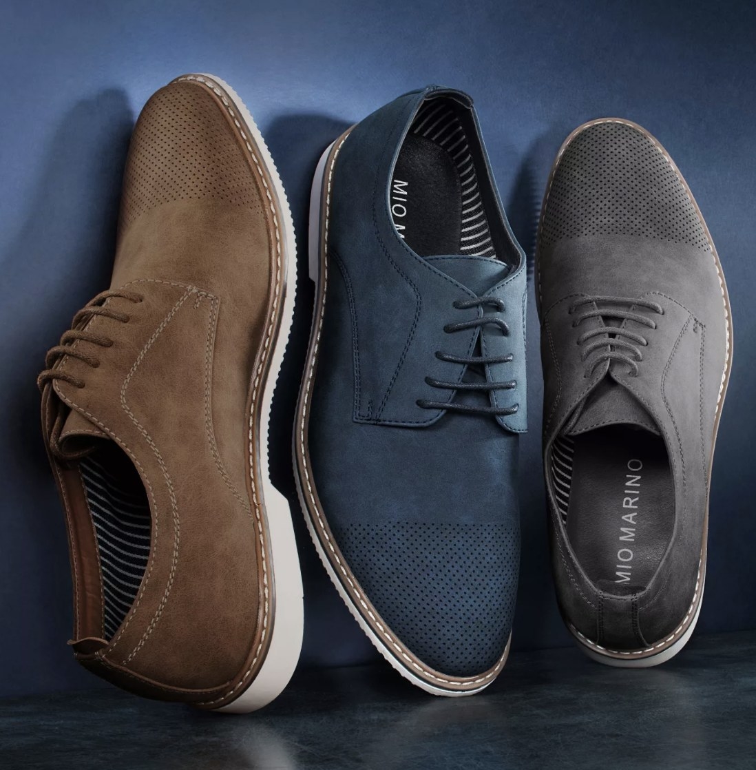 There are one brown, blue and grey shoe laid against a blue background