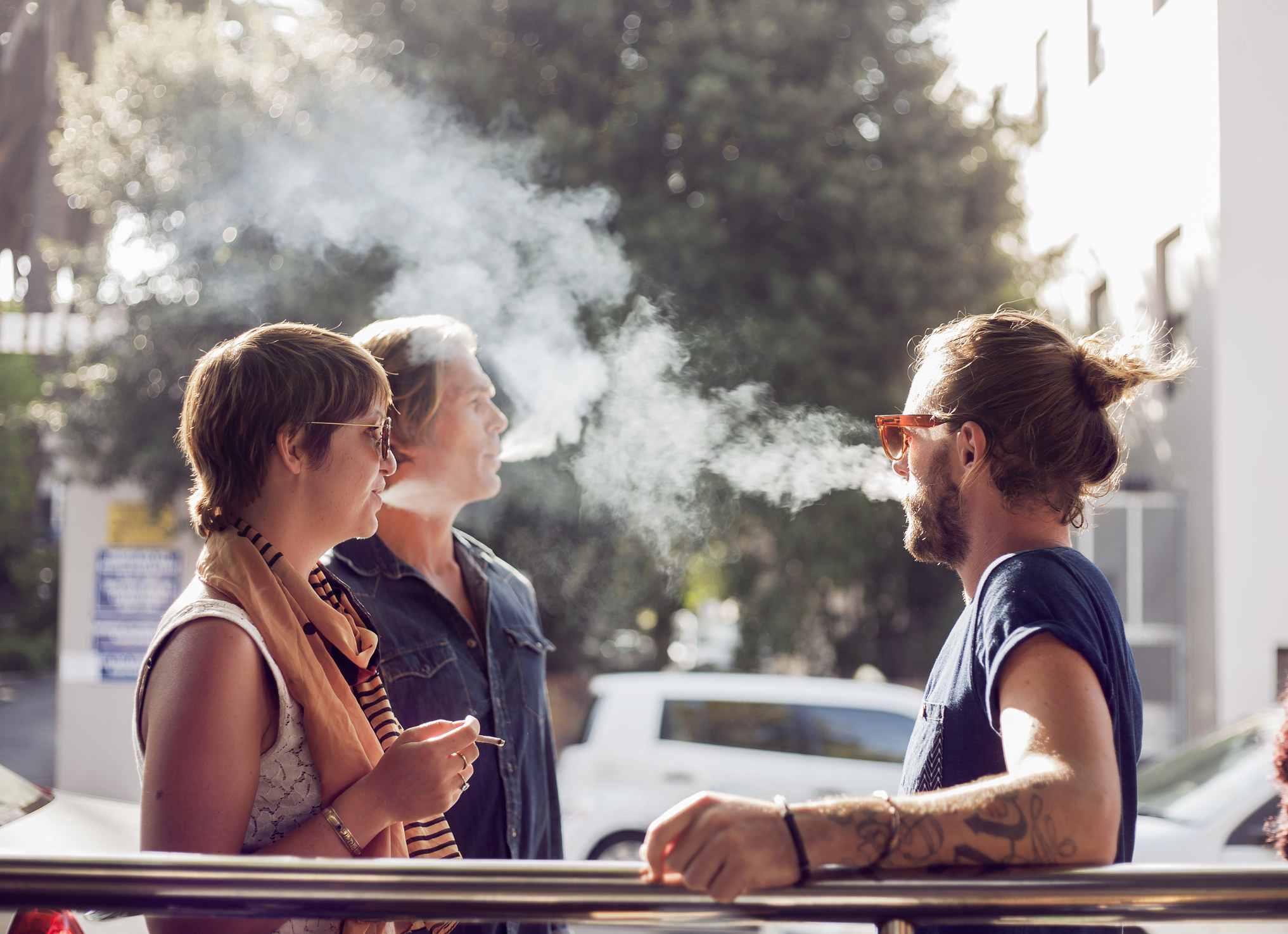 Three people standing outside and smoking