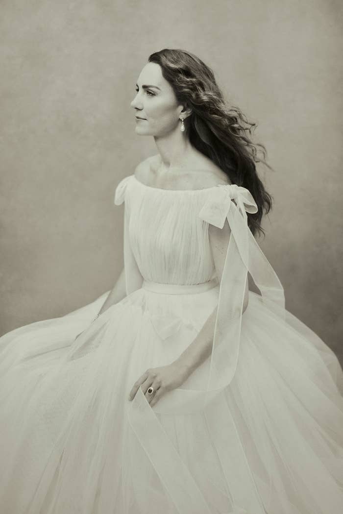 A black-and-white profile view of Kate with long hair, wearing an off-the-shoulder gown